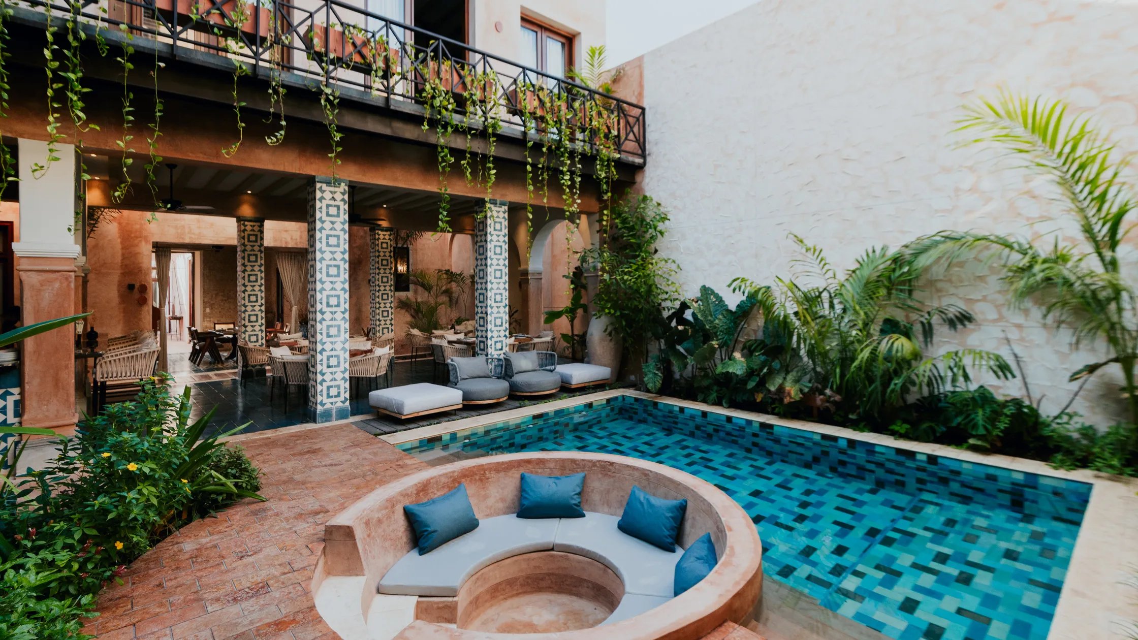 Courtyard of Hotel Cigno in Mérida with patterned tile columns, hanging vines and a turquoise plunge pool